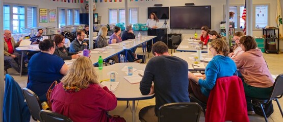 image of people sitting at round tables in a classroom