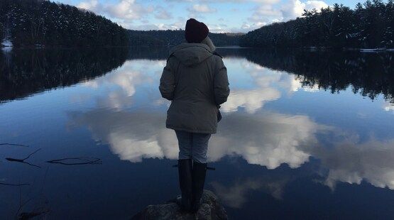 person standing by the water looking towards the water