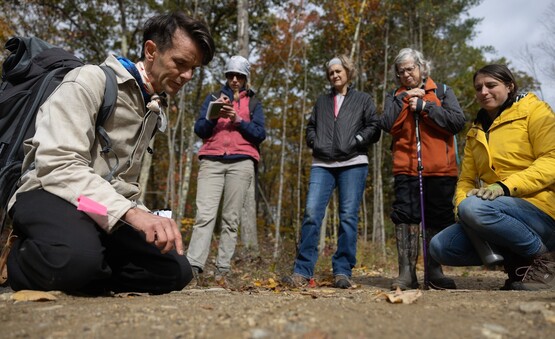 A group of people looking at an instructor teaching wildlife tracking skills