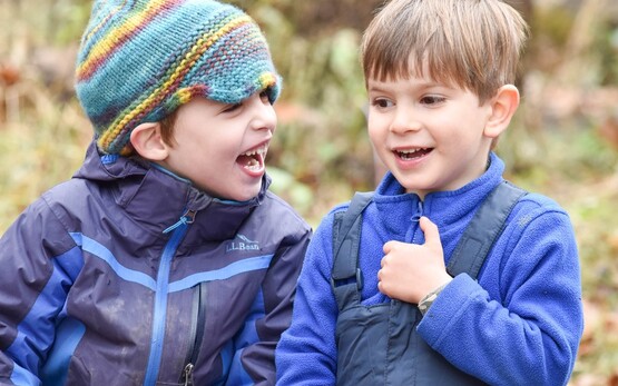 Two young boys sitting together in warm outdoor clothes.