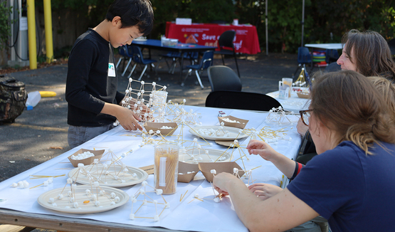 A young person putting together a structure made of marshmallows and skewer sticks.