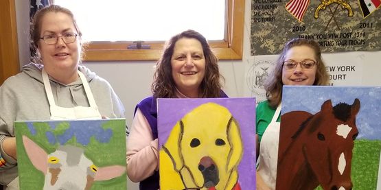 Four Women hold paintings of their pets they just made.