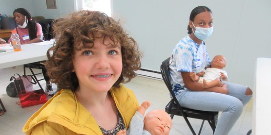 two children sit with plastic babies on their laps