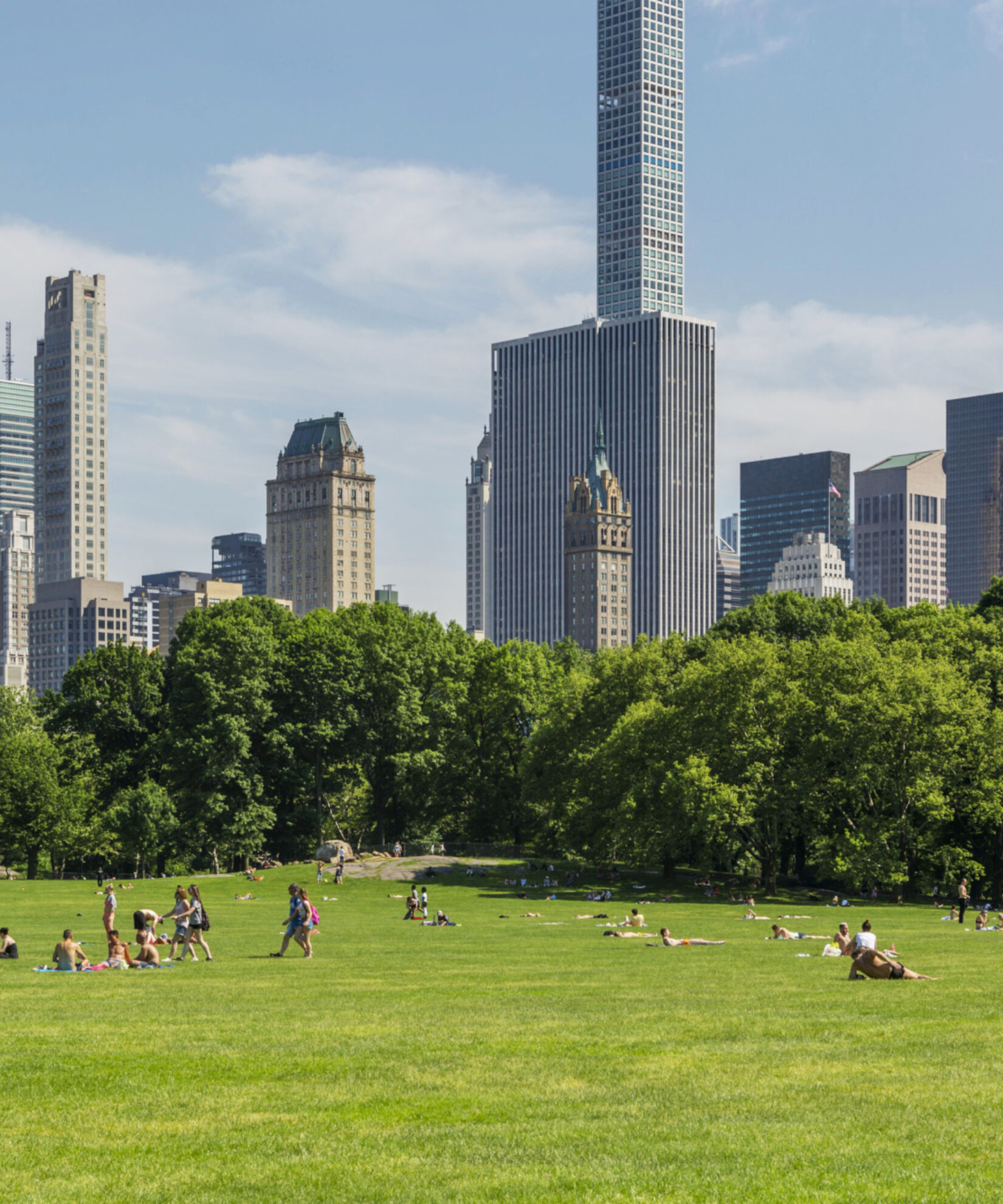 Parkgoers lounge on Sheep Meadow, with the skyscrapers of Manhattan's East Side filling the horizon.