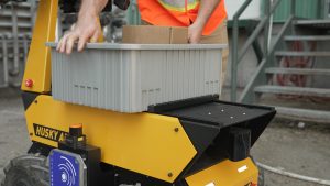 A worker placing a bin of materials onto the Husky AMP Transporter Configuration