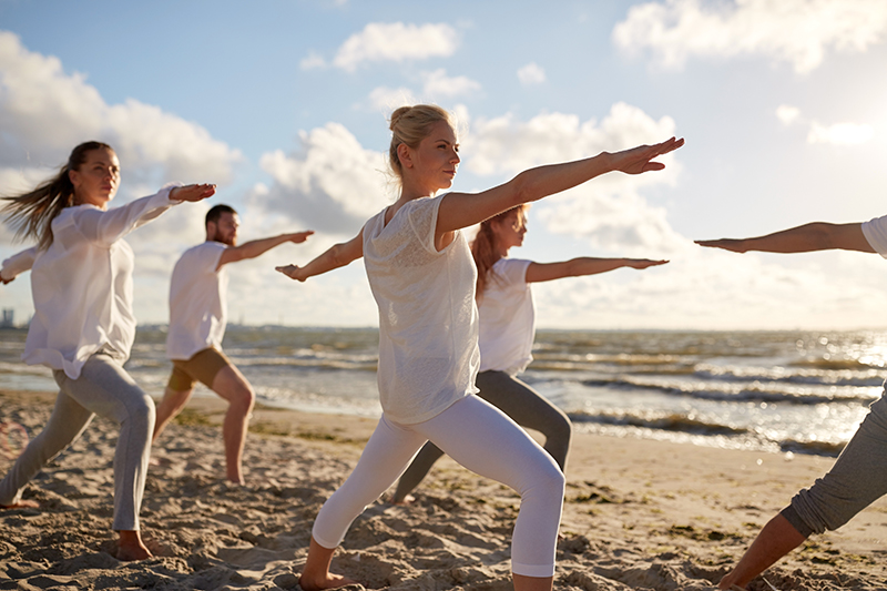 People doing yoga poses on beach
