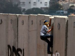 Occupation Drama
: Palestinian protester climbs the Israeli separation wall near a West Bank Jewish settlement.				