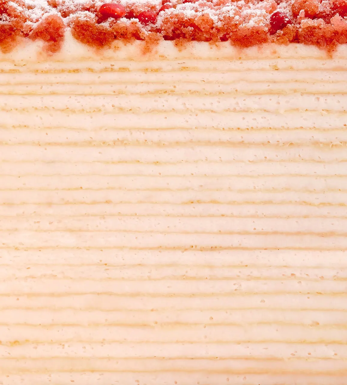 Pink Pearl Mille Crêpes with a pink topping, showcasing alternating layers of creamy filling and cake