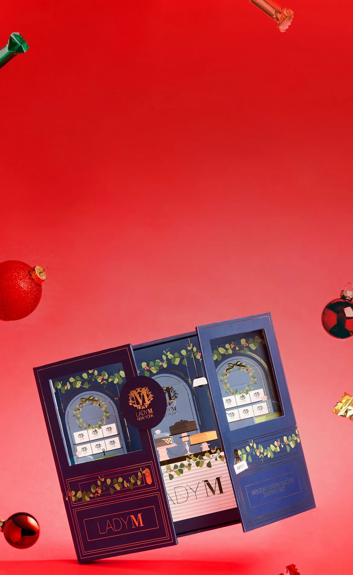 Lady M Holiday Crêpe Biscuit Tasting Set gift boxes displayed with festive red and green ornaments on a vibrant red and pink gradient background