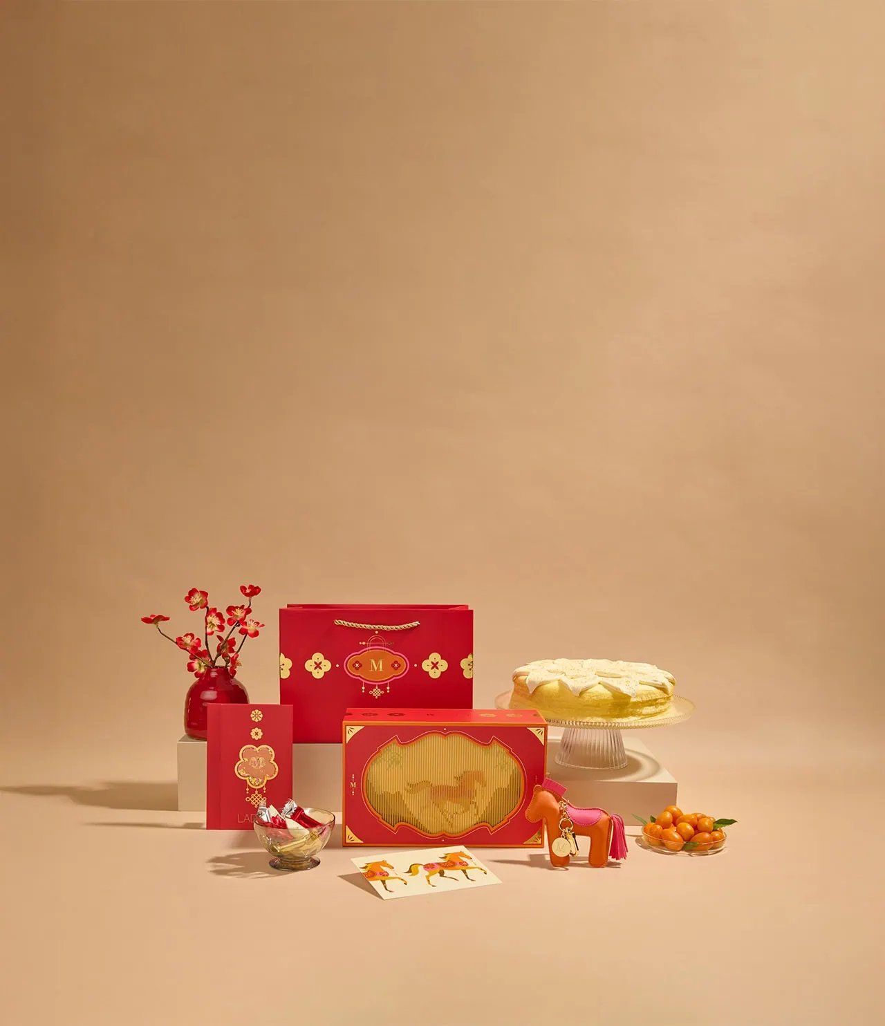 Year of the Horse Cake Bundle featuring Orange Mille Crêpes cake alongside the gift set with decorative bag, vegan leather horse keepsake, red envelopes, greeting card, and mini crêpe biscuits