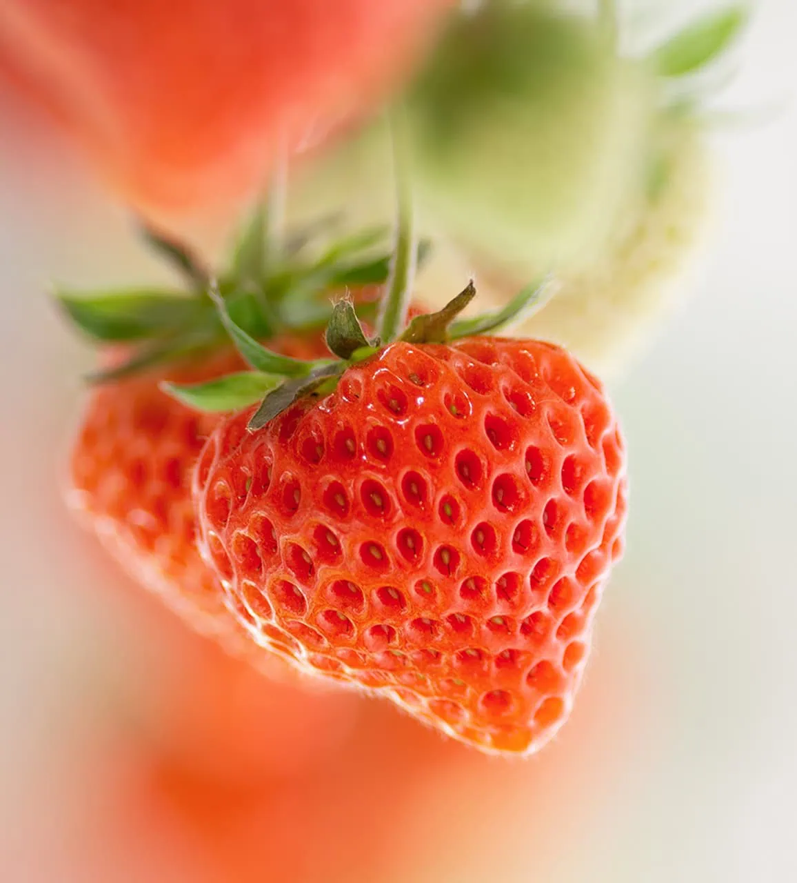 A close-up of a ripe strawberry with its characteristic seeds and green leaves.