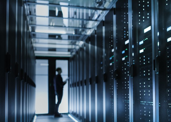 Image of a businessman standing next to data servers