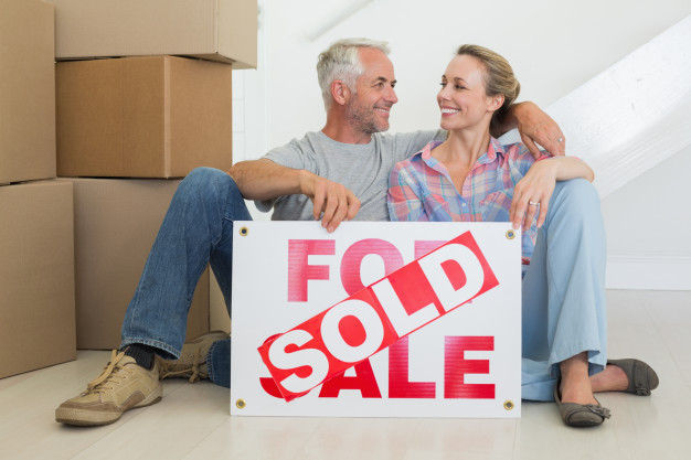happy-couple-sitting-floor-with-sold-sign_13339-152154.jpg