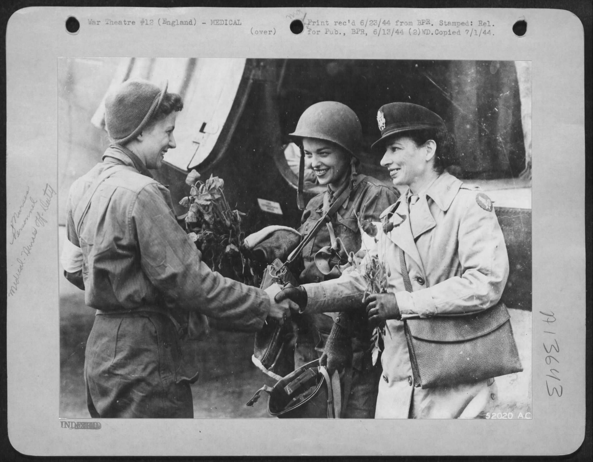 Poppies from France. 2nd Lt. Suella Bernard smiles and shakes hands with Lt. Ofster, head nurse, while 2nd Lt. Mary Jane Brown of Columbus, Ohio, looks on. Nurse Brown brought poppies together with wounded from a beach head in Normandy.