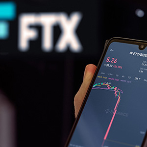 Image of a hand holding phone looking at stock chart of FTX