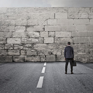 Image of a man facing a tall stone wall