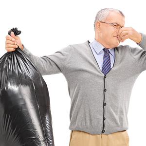 Image of a man holding a bag of trash and plugging his nose