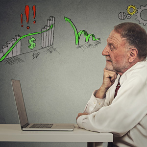 Image of a man sitting at a table and looking at a stock chart