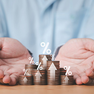 Image of two hands holding several piles of coins with arrows and percent signs on them.