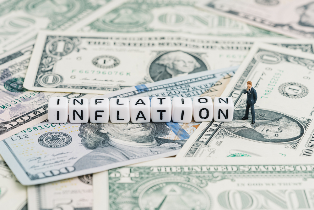 Miniature people businessman standing and wise thinking with cube block combine word Inflation on US dollar