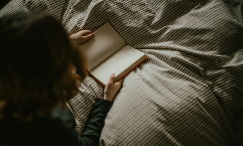 Child reading a book in bed.