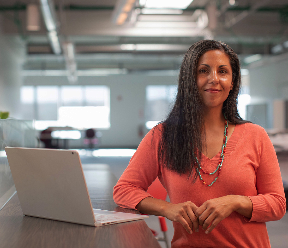 Photo of a woman standing by a laptop