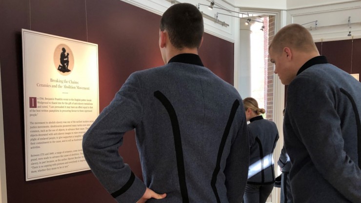 Students in cadet uniforms view an exhibit about the abolitionist movement