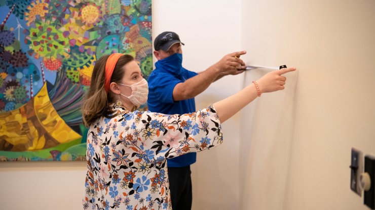 Several students carefully hanging a painting