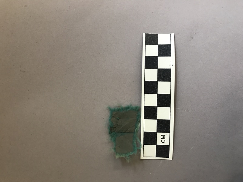 This artifact is a gray nylon cloth with a blue outer embroidery. Nylon was not created until the early 20th century as a cheaper alternative to silk.