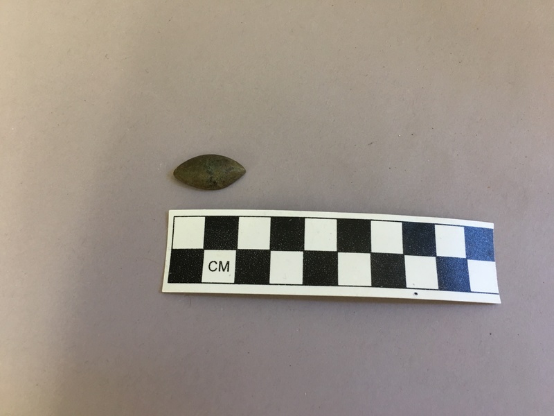 Front view of pewter button excavated from unit H931, Level 3, depth of 68-80cm. Note the plainness of the button and the absence of decorative detail.