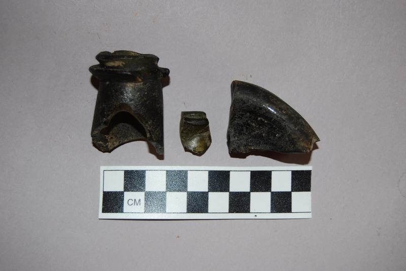 These broken shards come from the stem and base of an 19th century dark green wine bottle. We were able to date it by estimating the circumference of the base. Students at the college would have stored and drank this wine despite specific rules against doing so set by the University.