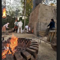 This image shows a team loading wood into a brick clamp at Colonial Williamsburg.