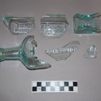 Six fragments of a bottle of Hood's Sarsaparilla, a popular brand in the late 19th and early 20th Centuries that was produced in Lowell, MA. Embossed lettering indicates the contents and manufacturer.