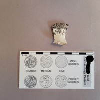 Brown transferprint ceramic sherd (front of design). The floral motif and stippled effect can be seen along the top edge of this photo.