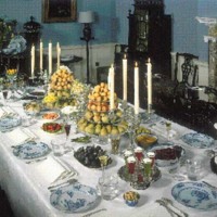 The painting displays an elaborately set table that would be typical of an upperclass home in the late 18th century. The plates displayed are made of fine porcelain China, a style that pearlware was made to replicate. The ornamentation of the scene signifies wealth and high standing within society. It is fitting, then, that wealthy students at Harvard would want to display their families' fortunes by bringing such dining ware with them to school. Even if their plates were not made of porcelain themselves, they were made of the next best thing.