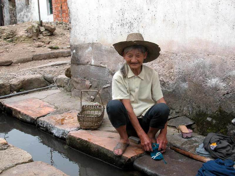 A villager washing clothes at the ditch flowing through the village