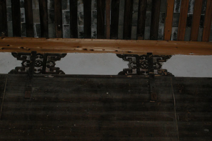Designs at the top of roof beam on back wall, left side of hall.