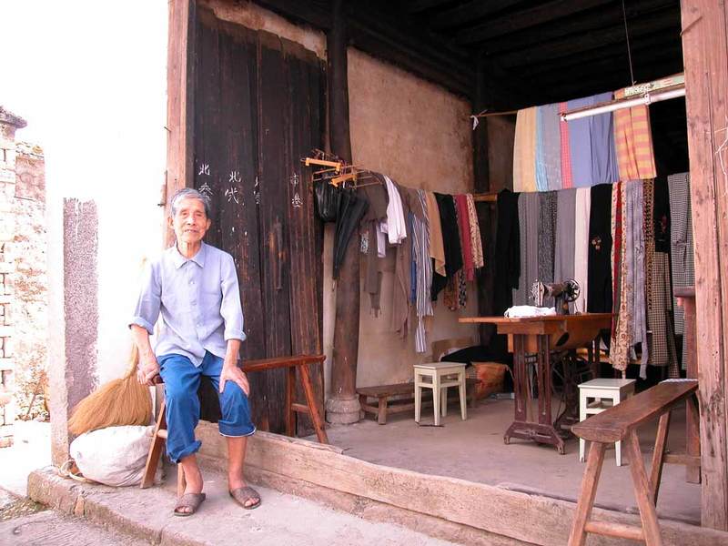 An old man sitting at a tailor`s shop An old man sitting at a tailor`s shop