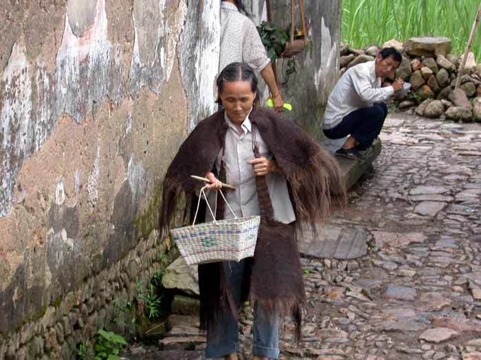 A woman wearing a raincoat carrying a basket on the street A woman wearing a raincoat carrying a basket on the street
