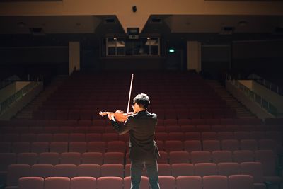 Man playing the violin in an empty auditorium