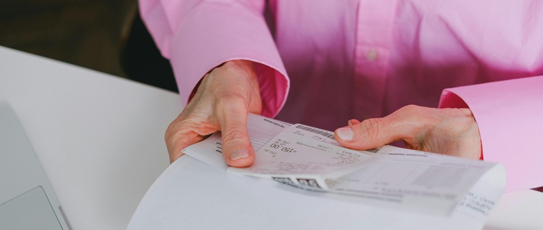Person holding paper receipts to be digitized and entered into automated invoice processing software.
