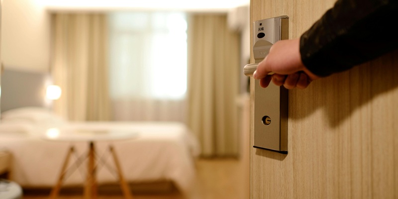 Hand opening hotel room door showing convenient check in by email automation