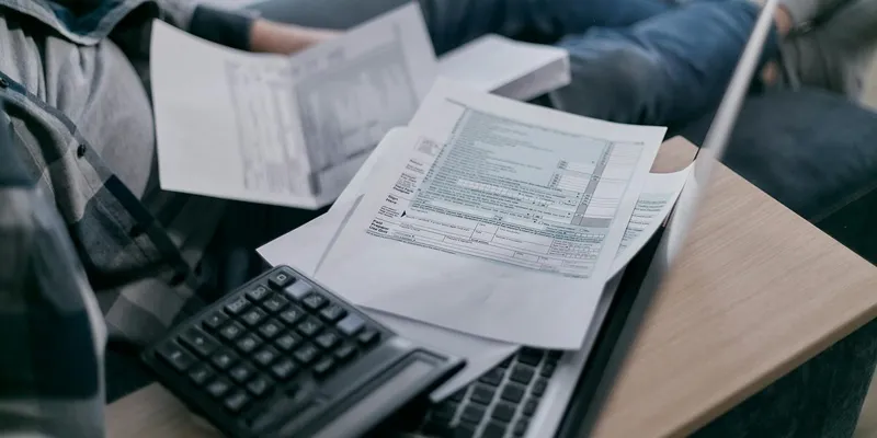 Tax forms and calculator on a laptop keyboard