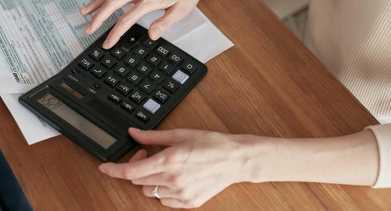 Hands using a calculator on an invoice