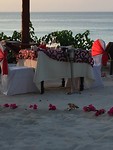 Gedekte tafel op het strand met een hart van bloemen er om heen