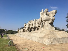 Beeld van de kolonisten met de indianen en slaven die alles sjouwen