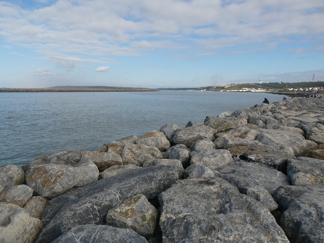 De dam met zicht op de rivier die vanuit het land de zee in stroomt