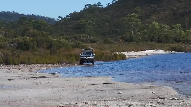 Auto door het water naar een ander stuk strand