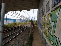 Pad tussen spoorbaan en viaductpijler, industriegebied Santander