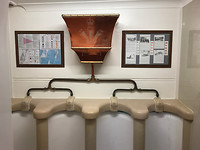Pissoir met stortbak in de RN&SYC, glimmend koper